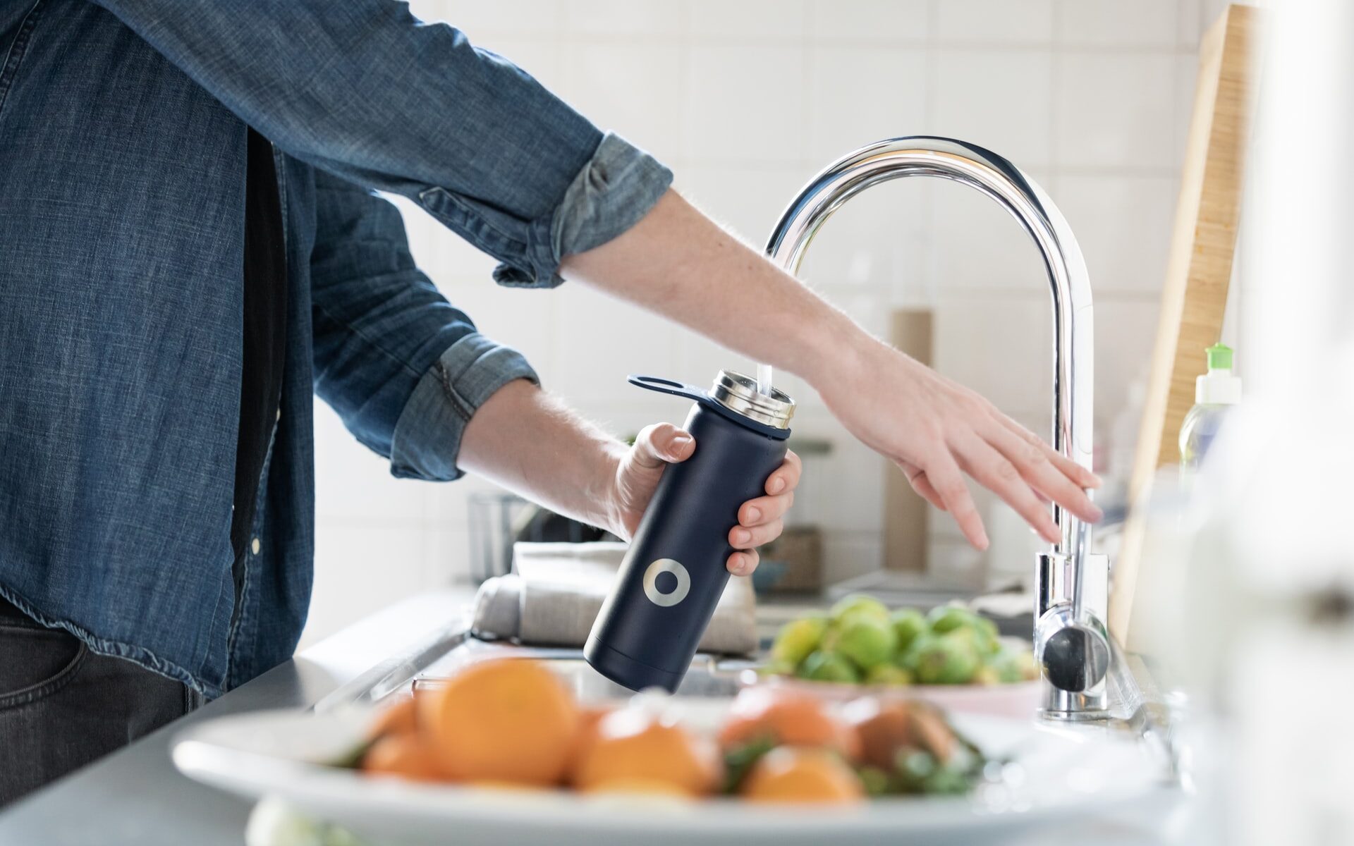 person fills up water bottle with filtered tap water