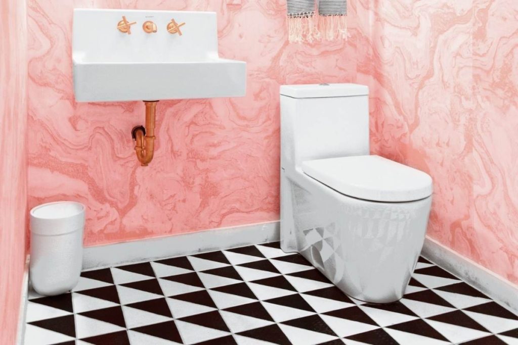 toilet room with pink walls and black and white tile floor