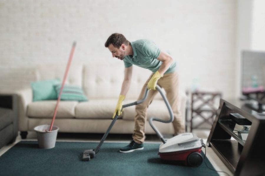man vacuuming living area to get rid of bed bugs in couch
