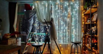 people hanging curtain lights in living room